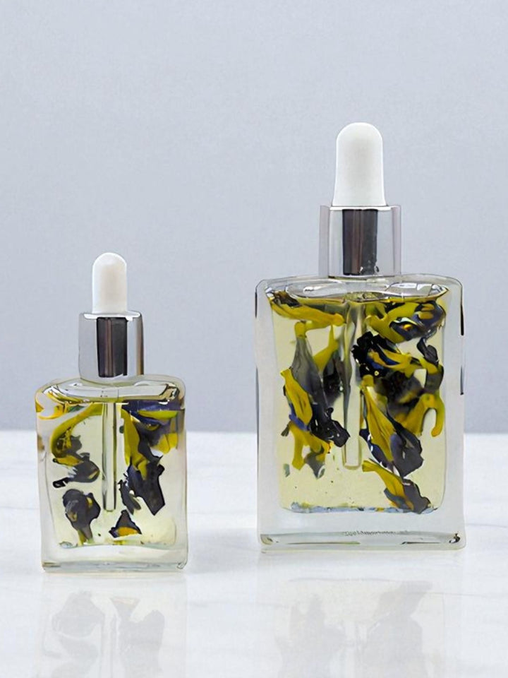 Bottle of Celestial Bloom Oil with butterfly pea flowers by Gaiaé. Botanical massage oil for glowing, soft skin.
