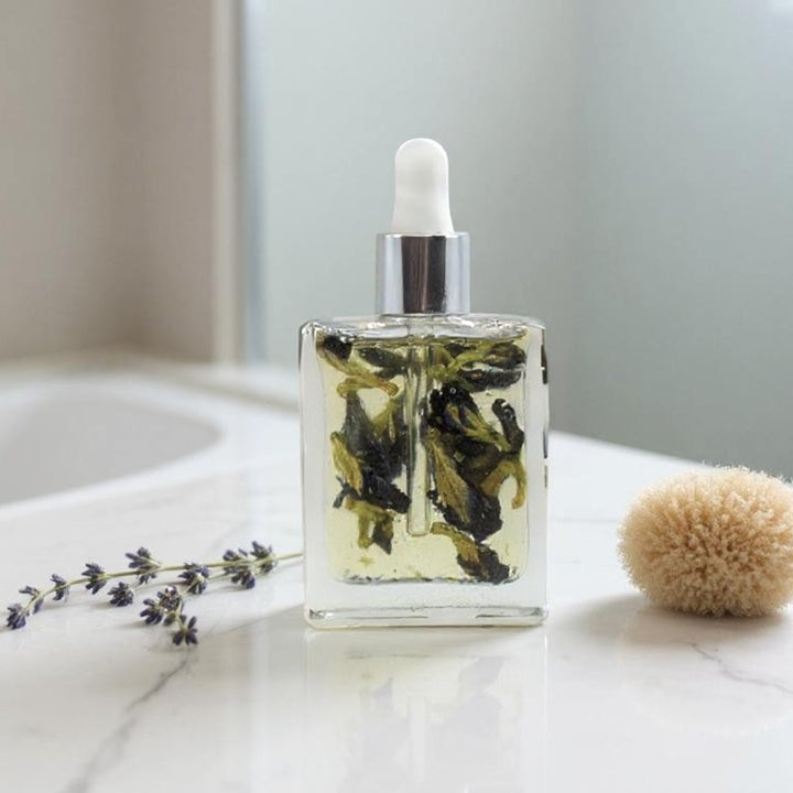 Bottle of Celestial Bloom Oil with butterfly pea flowers by Gaiaé. Botanical massage oil for glowing, soft skin.
