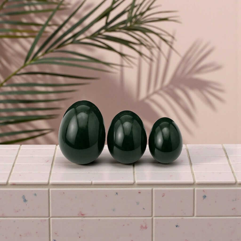 Three handcrafted jade yoni eggs displayed on a tiled surface, promoting feminine strength and healing. Gaiae Jade Yoni Egg Ritual Set • Nervous System Regulation 