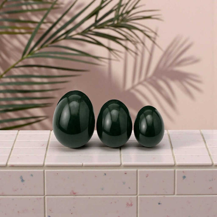 Three handcrafted jade yoni eggs displayed on a tiled surface, promoting feminine strength and healing. Gaiae Jade Yoni Egg Ritual Set • Nervous System Regulation 